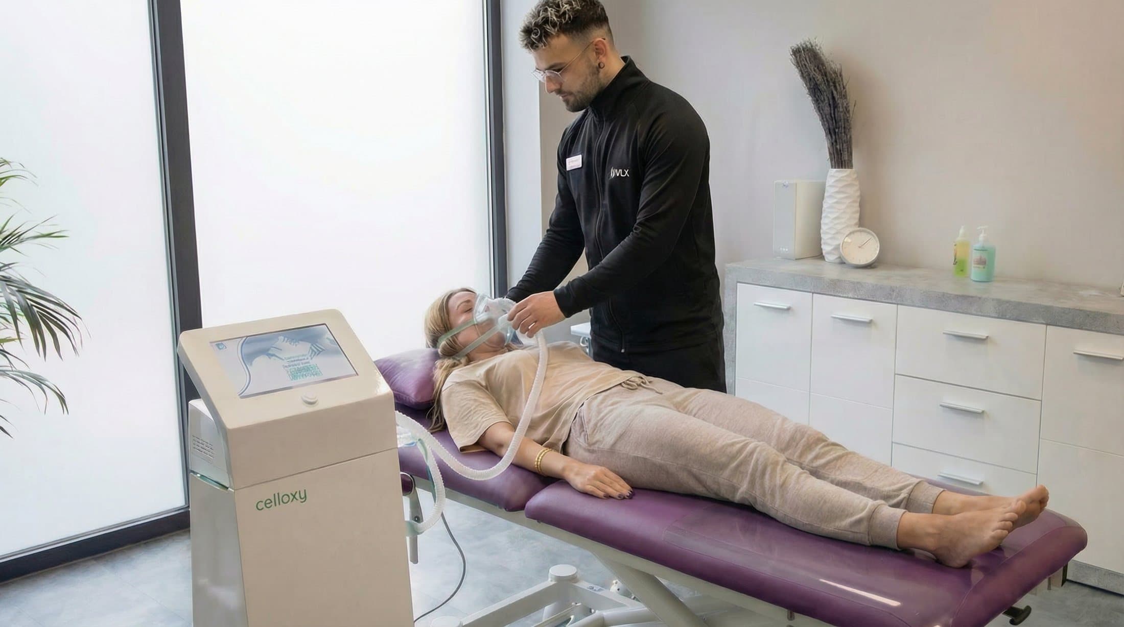 Therapeut setzt einer liegenden Kundin die Atemmaske für die IHHT-Anwendung auf