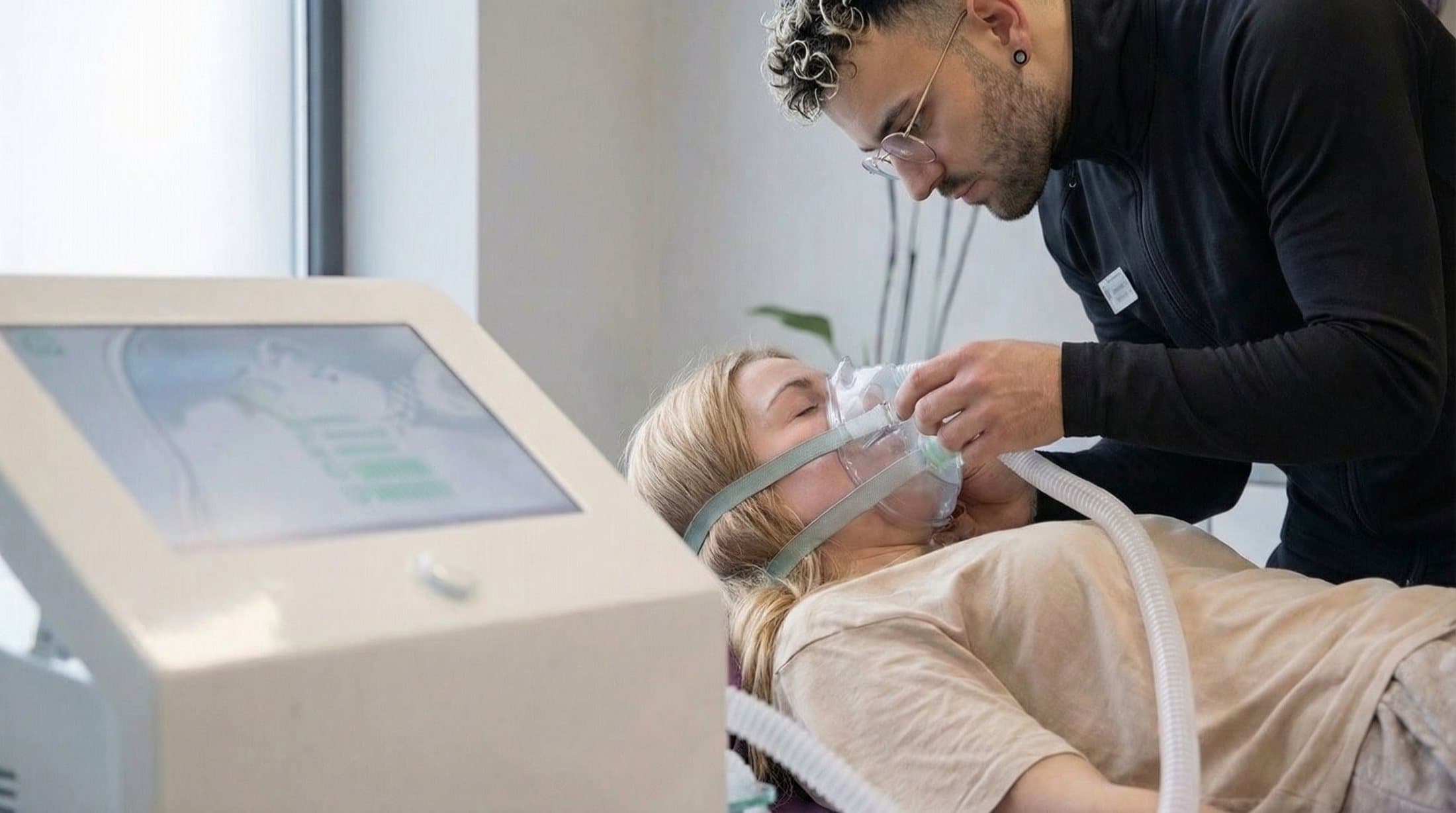 Therapeut setzt einer Kundin die Atemmaske für die IHHT-Anwendung auf