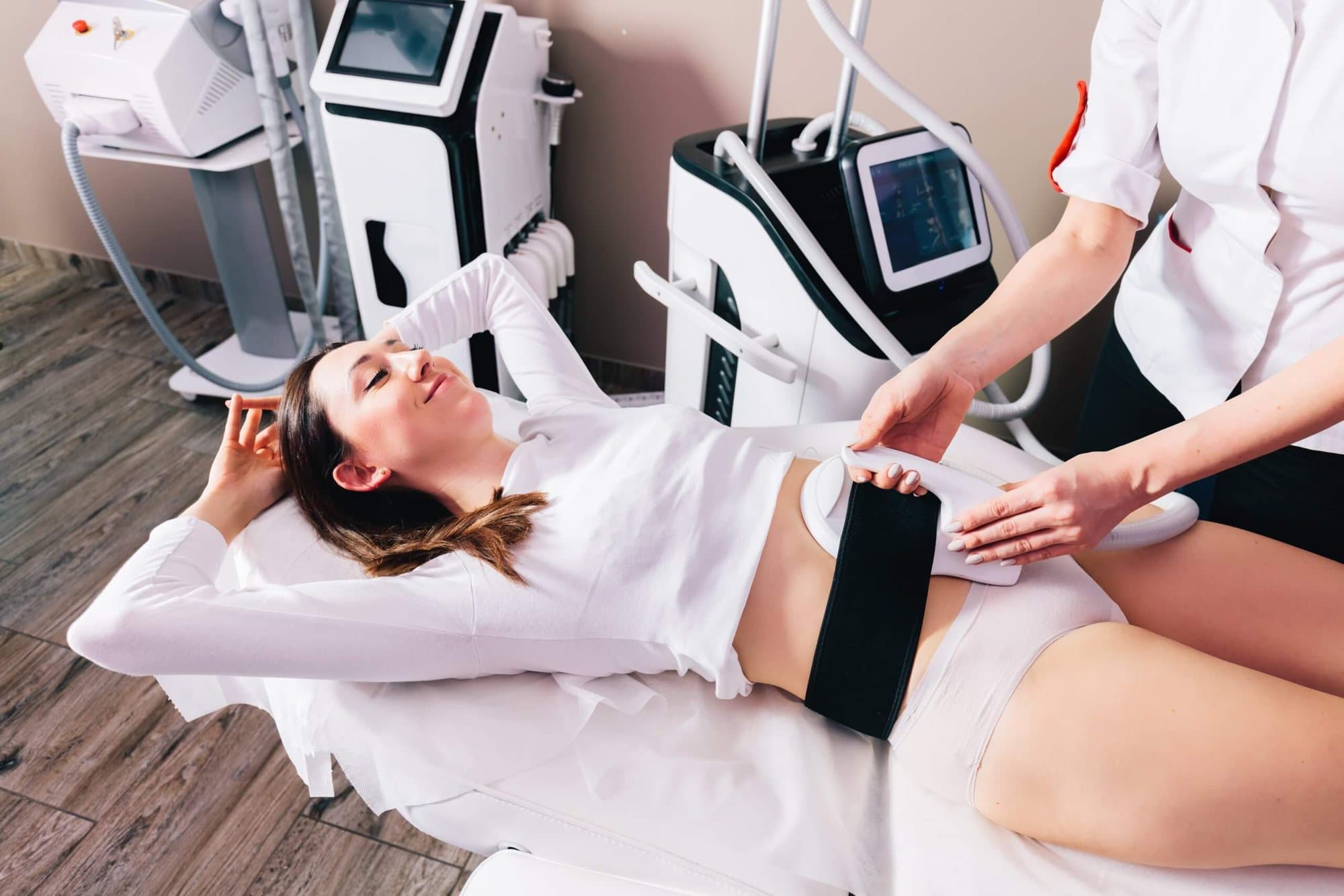 Therapeutin legt einer liegenden Kundin die Elektroden für Schlank werden im Liegen am Bauch an
